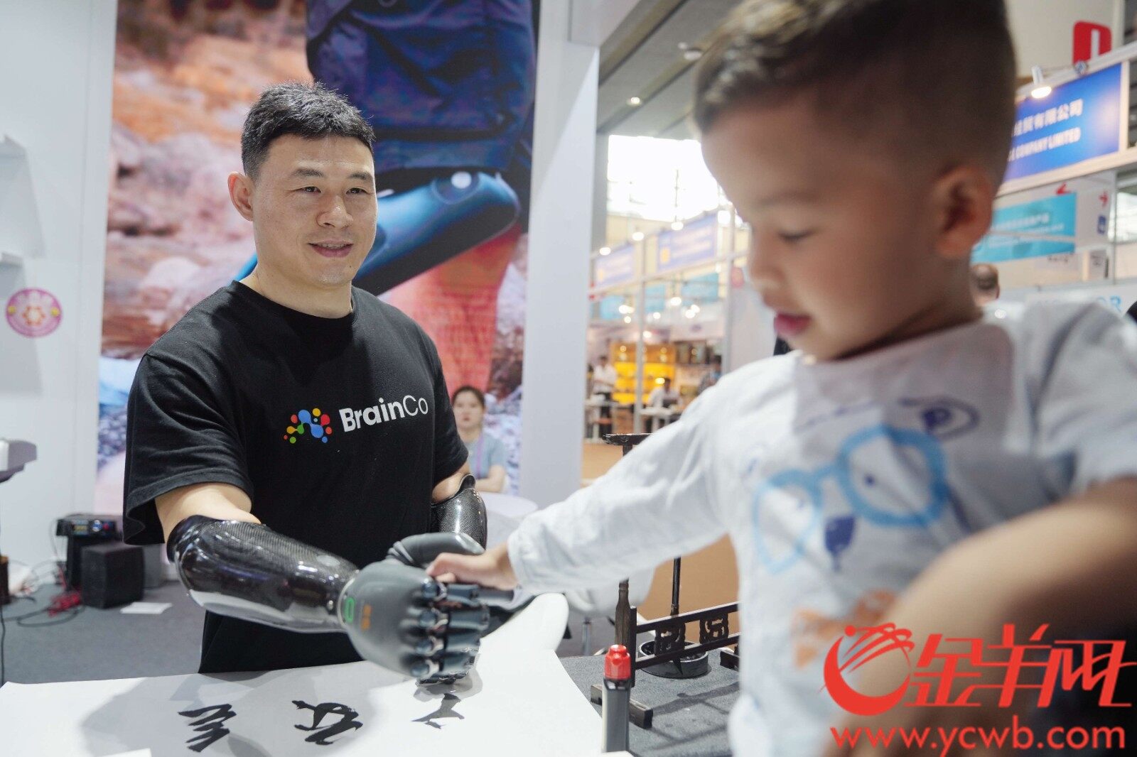 一名智能仿生手使用者在产品展位上用智能仿生手与小朋友握手